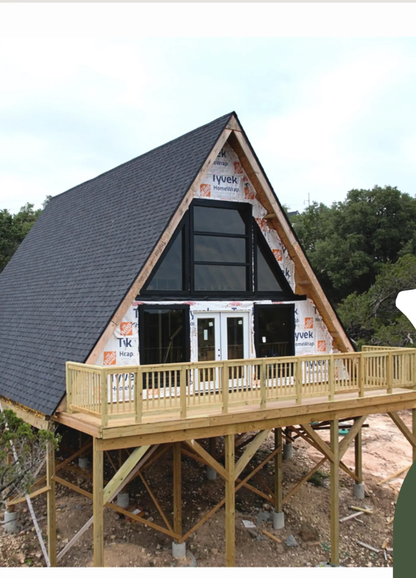 The A-frame with roof shingled, windows set and the elevated deck framed.