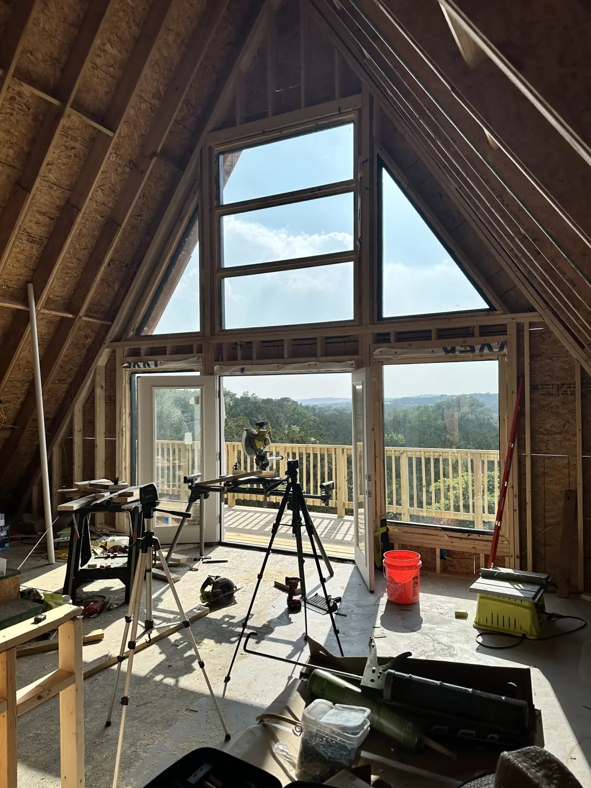 Inside the A-frame looking out through the tall gable window wall to the hills beyond.